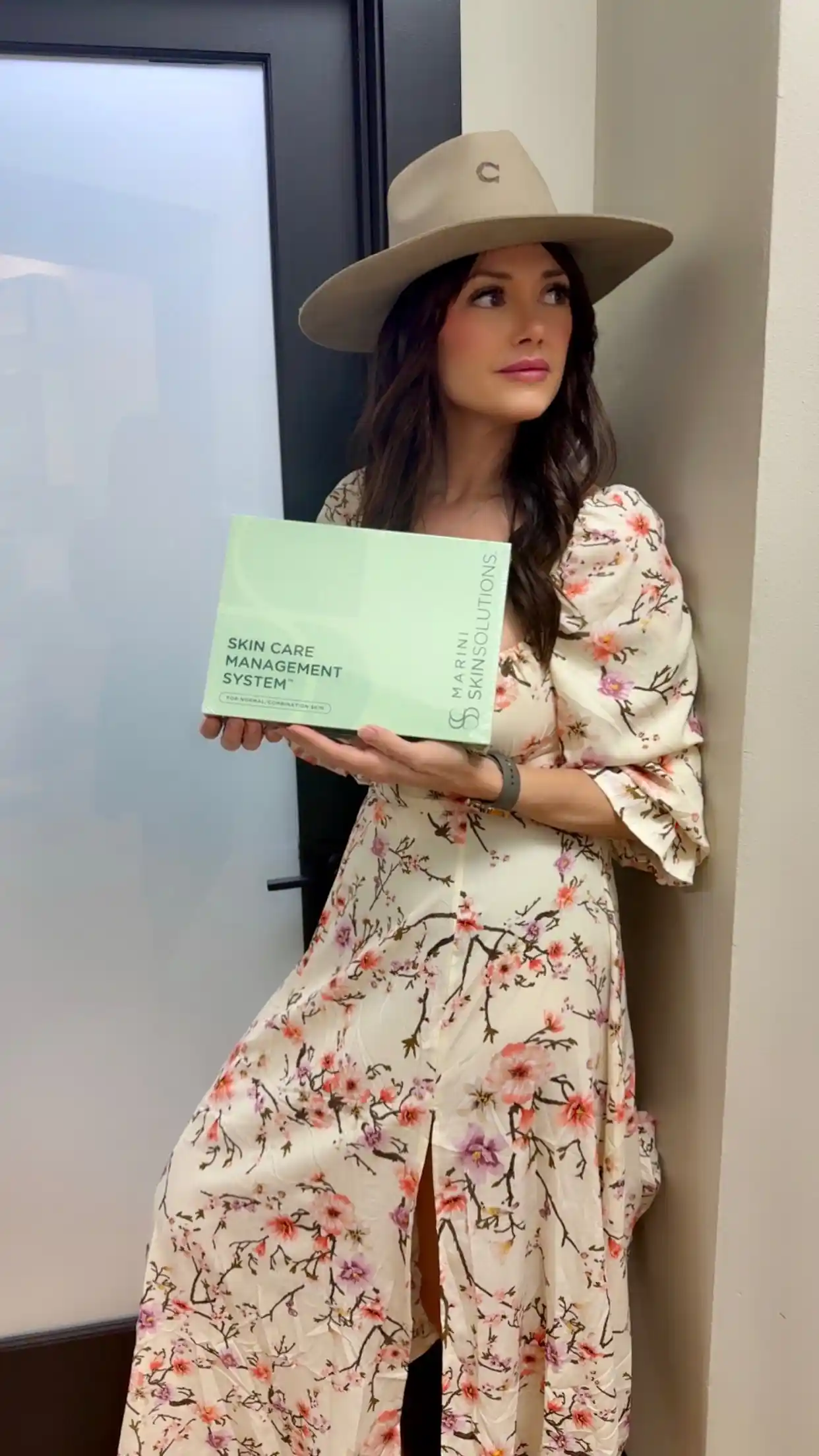 Owner of Remedy Aesthetics and Wellness, posing with skin care product