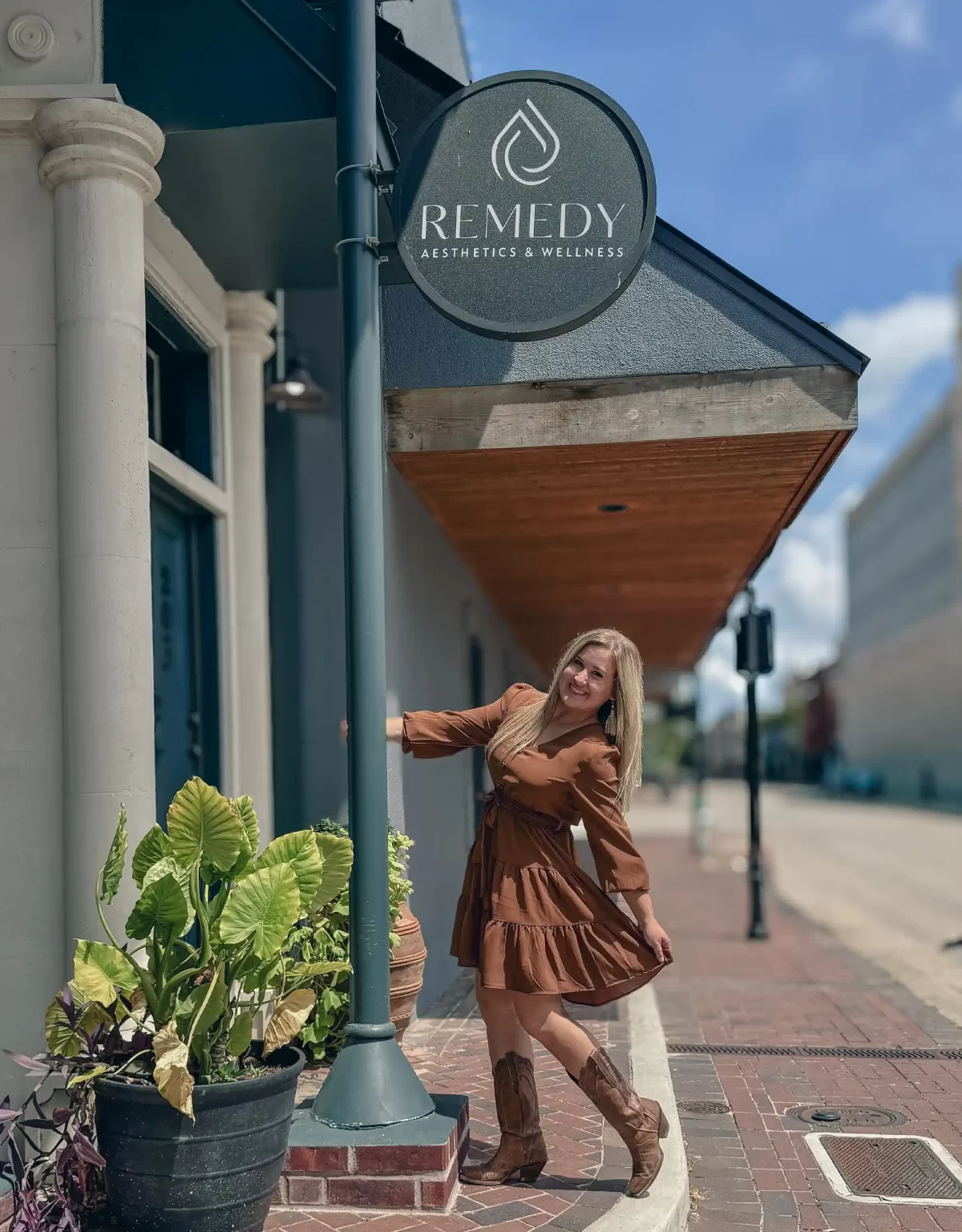 Staff posing under the Remedy Aesthetic and Wellness clinic sign